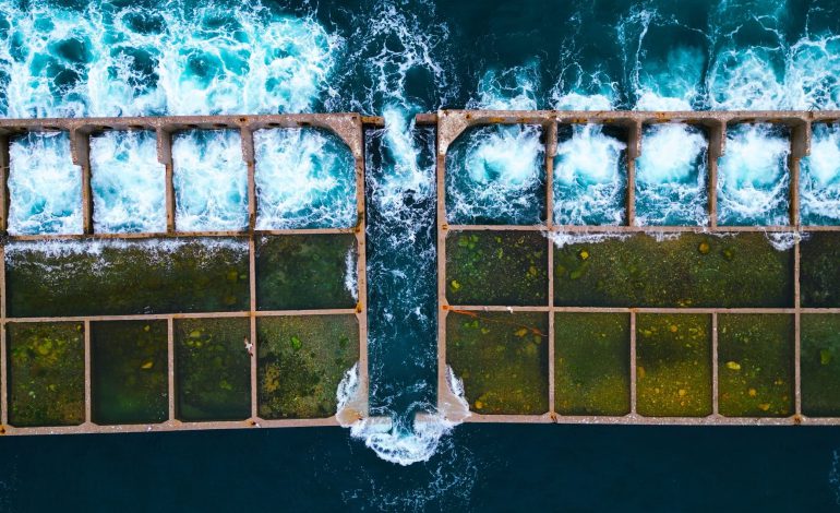 Top-down aerial image (90°) of the Piraeus cruise ship pier extension under construction, showing waves crashing against the pier, captured for Aerial Video services by Perigon Perspective.