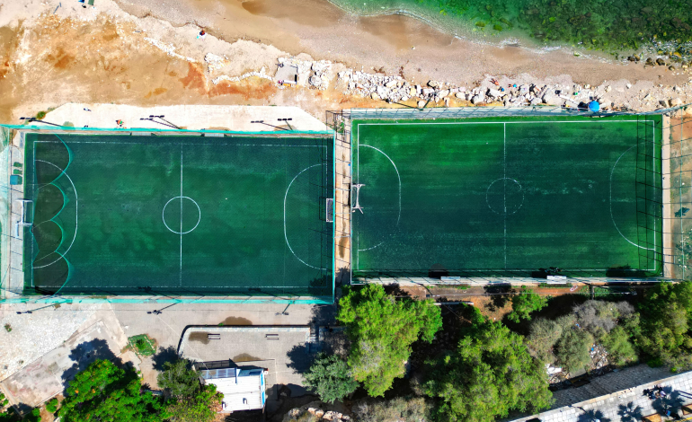 Top-down aerial image (90°) of two football fields by the sea in Votsalakia, Piraeus, showcasing aerial photography services by Perigon Perspective for businesses, municipalities, construction, tourism, and maritime enterprises.